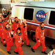 A photo of space shuttle astronauts walking past their transport vehicle.